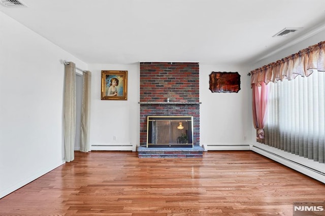 unfurnished living room featuring a baseboard heating unit, a brick fireplace, and hardwood / wood-style floors