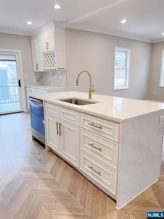 kitchen featuring white cabinets, dishwasher, sink, and an island with sink