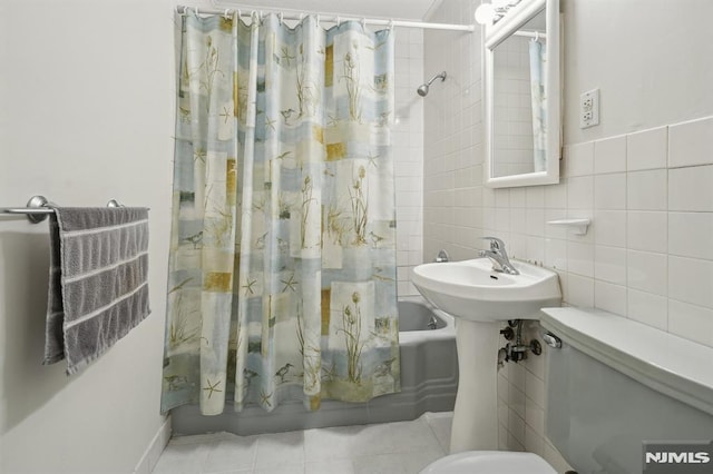 bathroom with toilet, tile patterned flooring, tile walls, and shower / bath combo with shower curtain