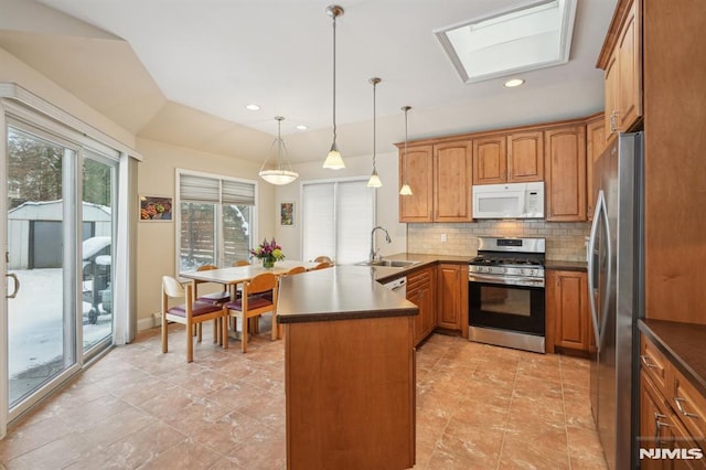 kitchen featuring sink, decorative light fixtures, kitchen peninsula, backsplash, and appliances with stainless steel finishes