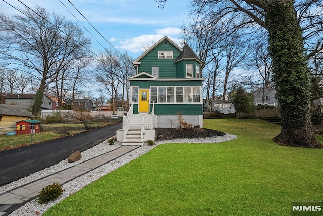 view of front facade with a sunroom and a front lawn