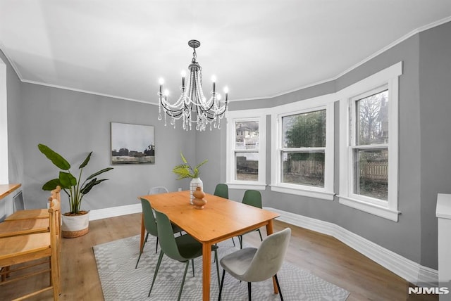 dining room with a notable chandelier, crown molding, and wood-type flooring