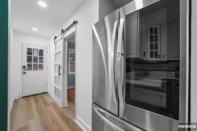 kitchen featuring light wood-type flooring, a barn door, and stainless steel refrigerator