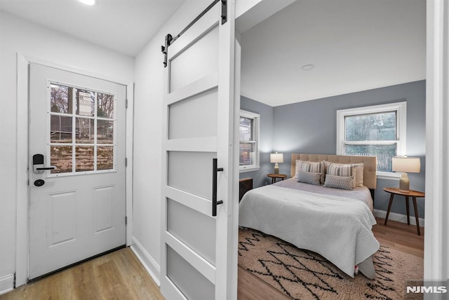 bedroom featuring light wood-type flooring and a barn door