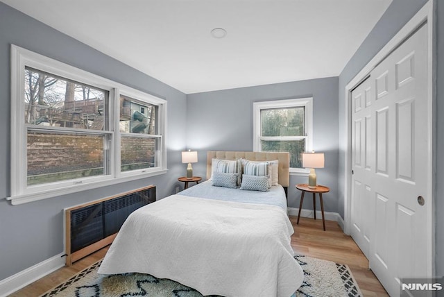 bedroom with a closet, radiator heating unit, and light hardwood / wood-style floors