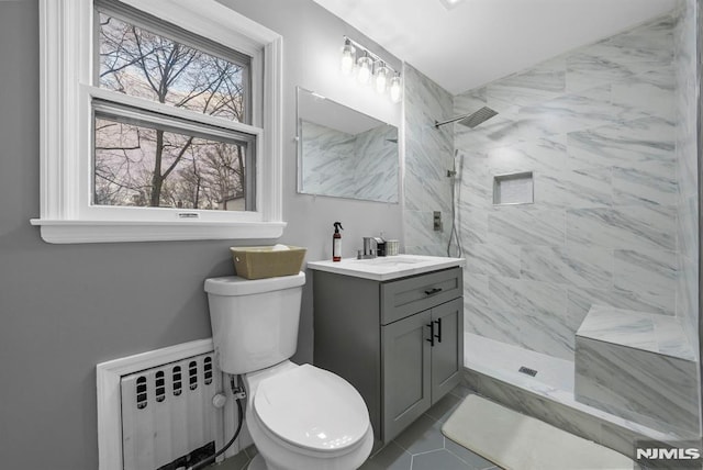 bathroom featuring radiator, toilet, tiled shower, and vanity