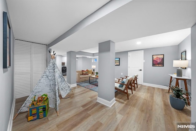 playroom with light hardwood / wood-style flooring and washer / dryer