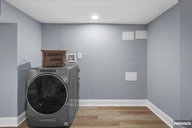 clothes washing area with washer / dryer and light wood-type flooring