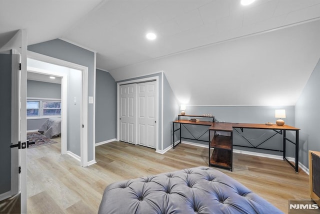 bedroom featuring vaulted ceiling, a closet, and light hardwood / wood-style floors