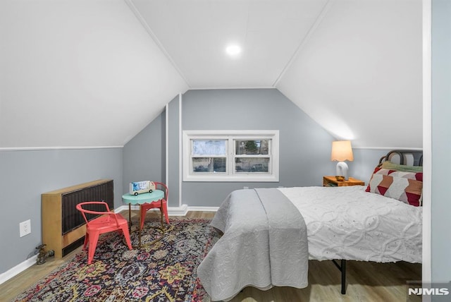 bedroom featuring lofted ceiling, hardwood / wood-style floors, and heating unit