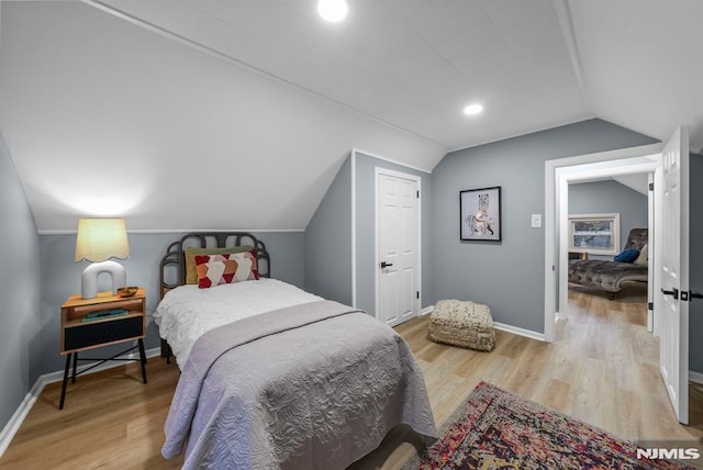 bedroom featuring lofted ceiling and light wood-type flooring