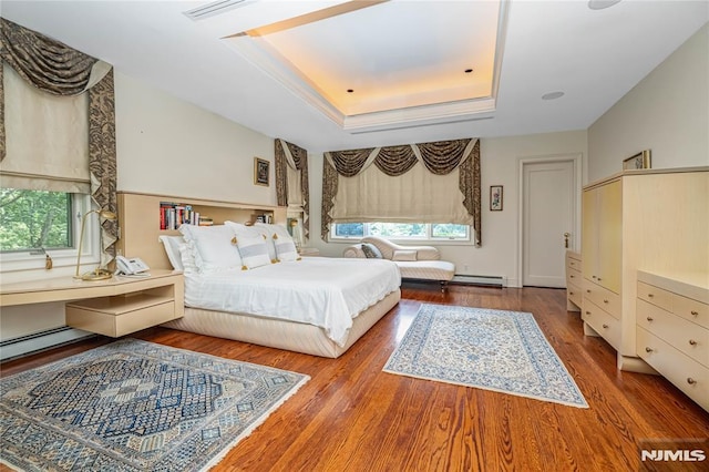 bedroom featuring a baseboard heating unit, hardwood / wood-style floors, and a tray ceiling