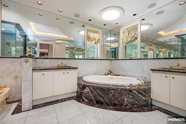 bathroom with a tray ceiling, vanity, a bidet, and independent shower and bath