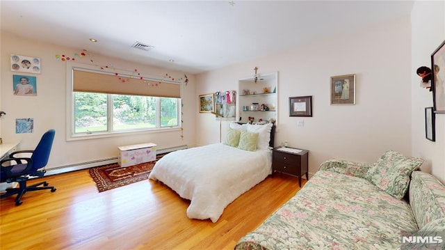 bedroom with baseboard heating and hardwood / wood-style floors