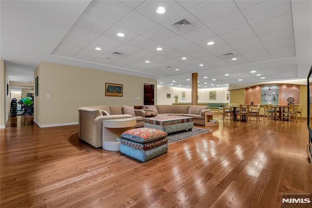 living room with hardwood / wood-style floors and a drop ceiling