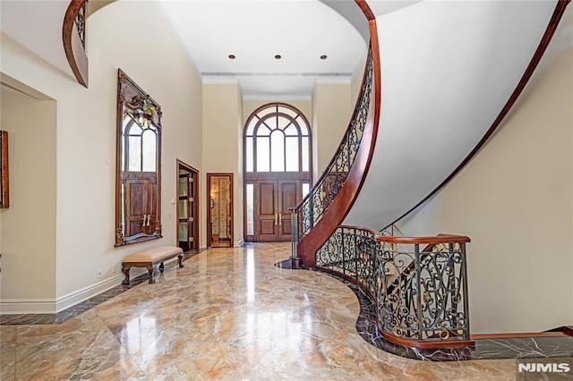 entryway with a high ceiling, crown molding, and a healthy amount of sunlight