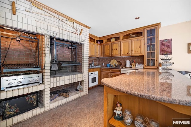 kitchen with sink, stone countertops, oven, and tasteful backsplash