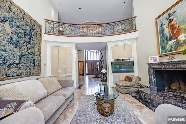 living room featuring a tiled fireplace and a towering ceiling