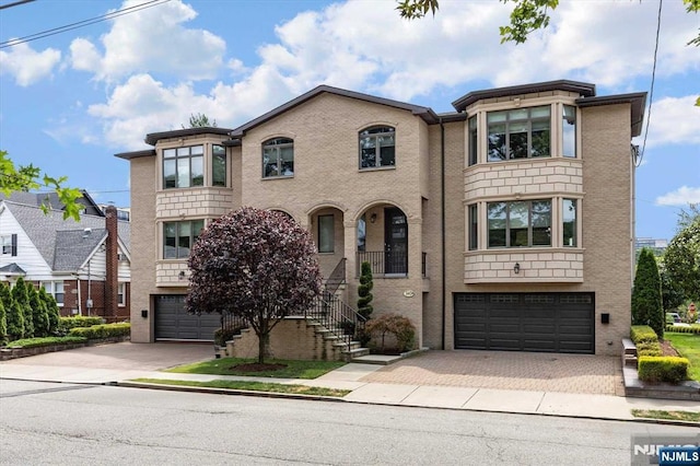 view of front facade with a garage, decorative driveway, and brick siding