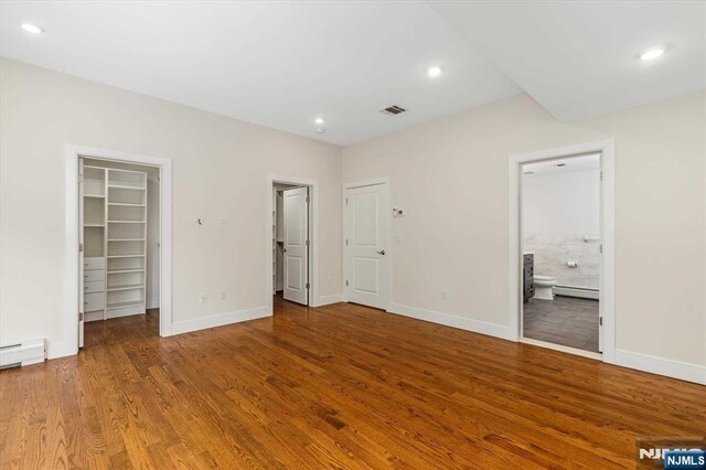 unfurnished bedroom featuring baseboards, visible vents, wood finished floors, and a spacious closet