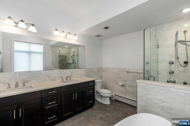 bathroom with a sink, a baseboard radiator, a stall shower, and visible vents