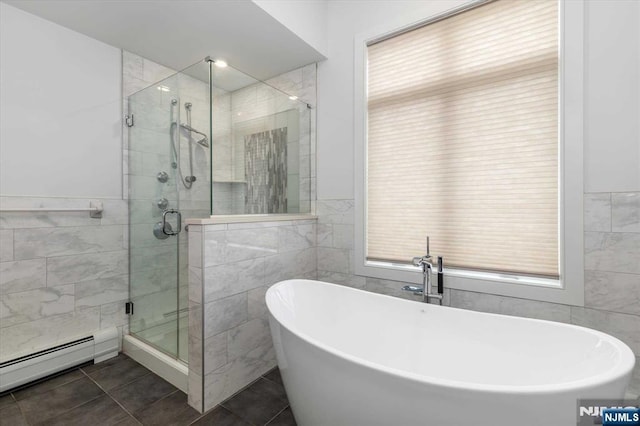 bathroom featuring tile patterned floors, a stall shower, baseboard heating, and tile walls