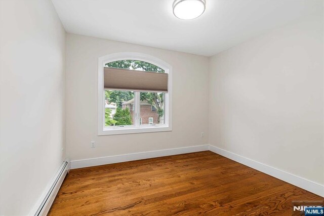 spare room featuring baseboards, wood finished floors, and baseboard heating
