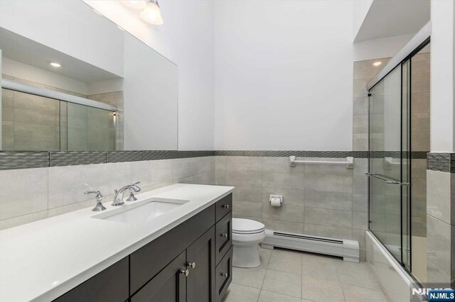 bathroom featuring vanity, toilet, tile patterned floors, tile walls, and a baseboard radiator