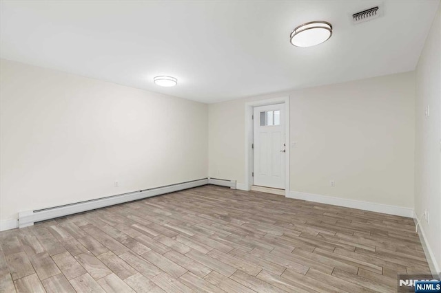 basement with baseboards, visible vents, baseboard heating, and light wood-style floors