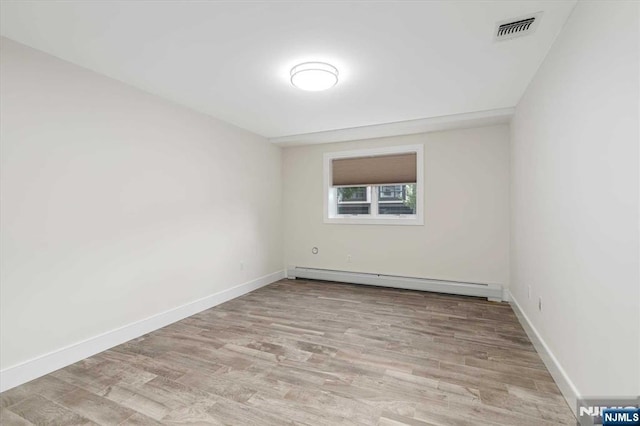 empty room with baseboards, a baseboard heating unit, visible vents, and light wood-style floors
