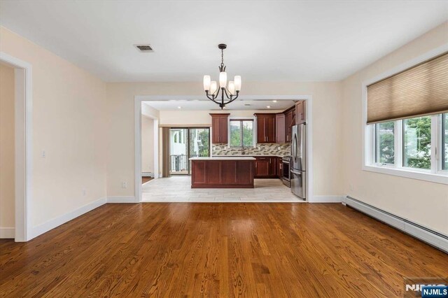 kitchen with visible vents, tasteful backsplash, light countertops, an inviting chandelier, and stainless steel appliances