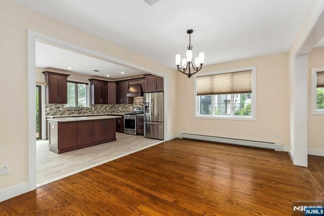 kitchen with dark brown cabinetry, appliances with stainless steel finishes, light countertops, a sink, and a baseboard heating unit