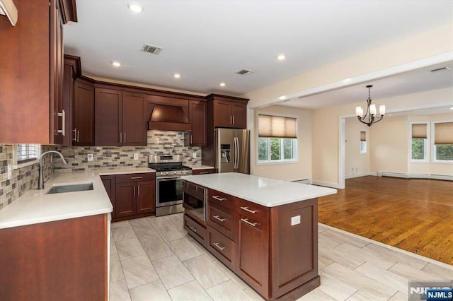 kitchen featuring an inviting chandelier, a sink, stainless steel appliances, visible vents, and custom exhaust hood