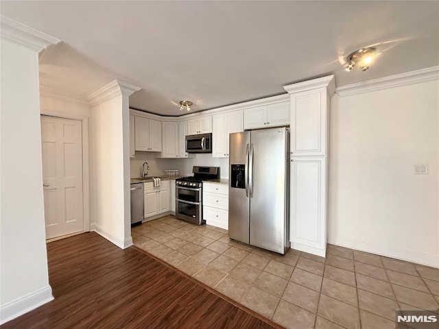 kitchen featuring light tile patterned floors, appliances with stainless steel finishes, crown molding, and white cabinetry