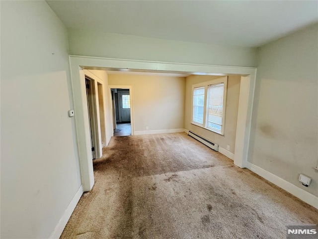 carpeted empty room with a baseboard heating unit