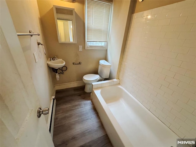 bathroom with wood-type flooring, a baseboard heating unit, sink, toilet, and a bath