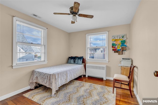 bedroom with ceiling fan, hardwood / wood-style flooring, and radiator heating unit