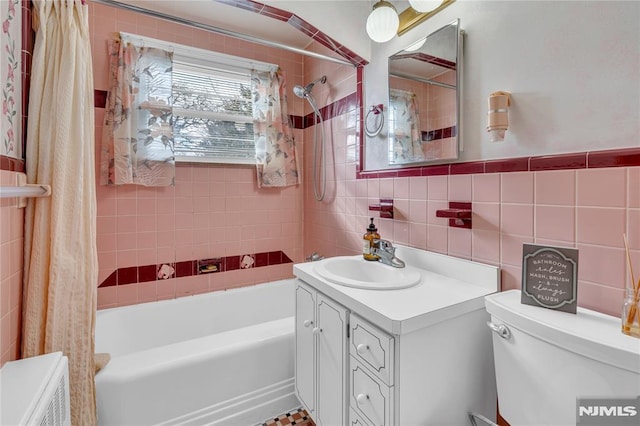 full bathroom with tiled shower / bath, vanity, decorative backsplash, tile walls, and toilet