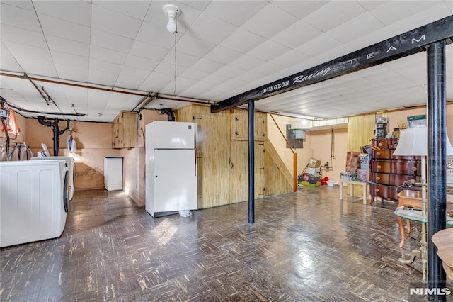 basement with white fridge, washer / dryer, and wooden walls