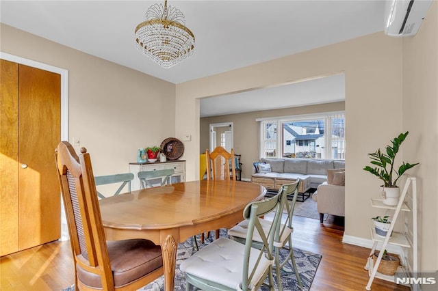 dining area with a wall mounted AC, a notable chandelier, and wood-type flooring