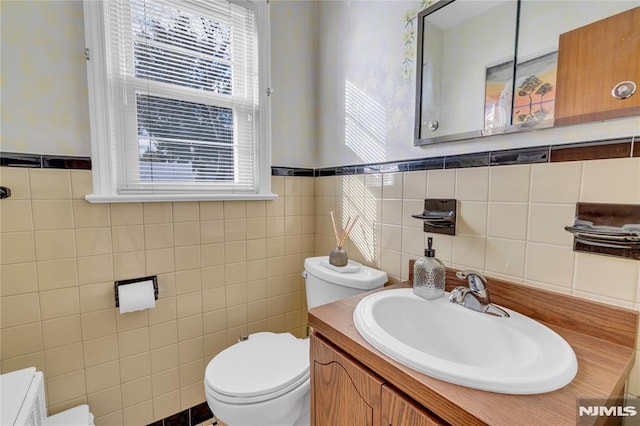 bathroom with tile walls, toilet, and vanity