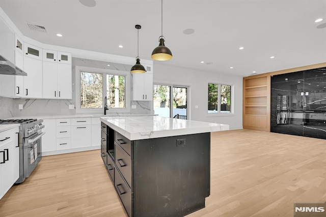 kitchen featuring a center island, pendant lighting, white cabinetry, and high end stainless steel range oven