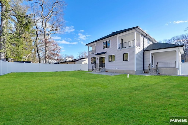 rear view of house with a lawn and a balcony