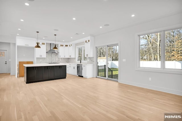 kitchen featuring decorative light fixtures, a center island, a wealth of natural light, white cabinetry, and wall chimney exhaust hood