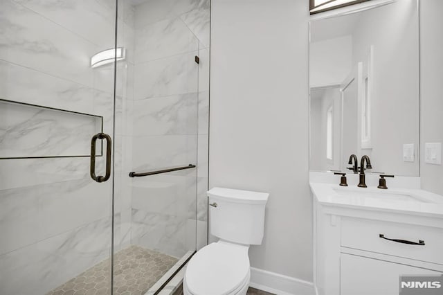 bathroom featuring a shower with shower door, vanity, and toilet