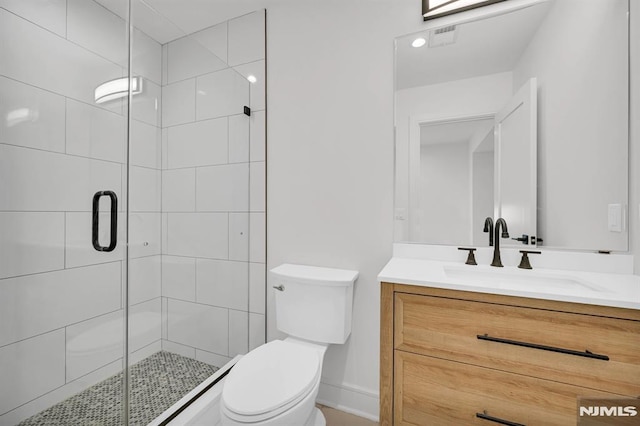 bathroom featuring toilet, a shower with door, and vanity