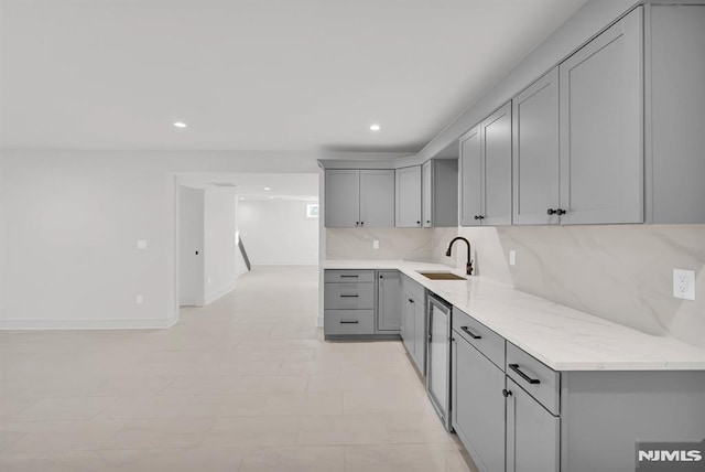 kitchen with light stone countertops, sink, backsplash, and gray cabinetry