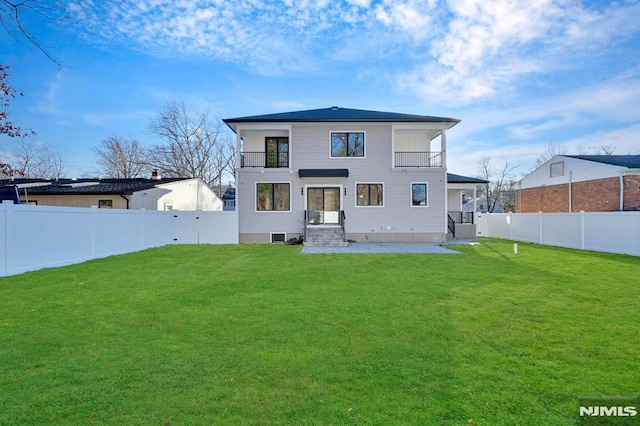 back of house featuring a lawn and a balcony