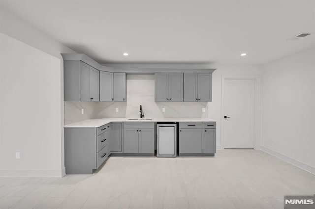 kitchen featuring gray cabinets, decorative backsplash, and sink