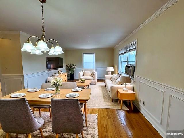 dining room featuring hardwood / wood-style floors, ornamental molding, cooling unit, and an inviting chandelier